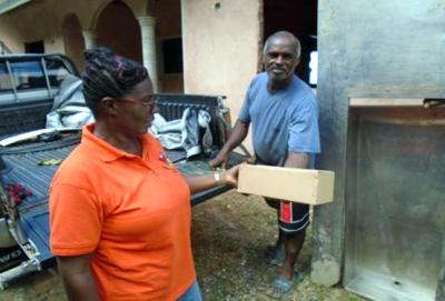 Caption: Sharon Boyce-Julien, Community Development Officer I, St. Andrew/St. David, Ministry of Community Development, Culture and the Arts assists in distributing kerosene lamps to affected residents in St Helena on December 2. (Photo courtesy the Ministry of Community Development, Culture and the Arts)