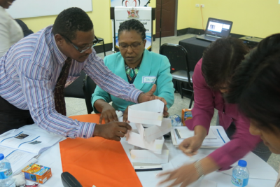 Getting it right: Permanent Secretary in the Ministry of Social Development and Family Services, Mrs Jacinta Bailey-Sobers (seated centre) assists Mr Troy Pollonais (standing left), Deputy Director of the Social Welfare Division and other senior staff of the Division engage in learning activities during the training session spearheaded by the Caribbean Leadership Programme.