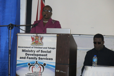 Caption: Minister of Social Development and Family Services, the Honourable Cherrie Ann Crichlow-Cockburn delivers the feature address at the event. Also photographed is the Master of Ceremonies and radio personality, Anthony 'Storming' Tom. (Photo courtesy the Ministry of Social Development and Family Services)