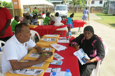 Caption: Premchand Ramdhin of the Ministry of Social Development and Family Services informs the attendee of the services offered by the Ministry during the South AIDS Support Group Community Knowledge and Health Fair at Dow Village, California, Couva. (Photo courtesy the Ministry of Social Development and Family Services)
