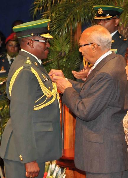 President George Maxwell Richards pins the Public Service Medal of Merit (Gold) on Major General Edmund Dillon, a former Chief of Defence Staff