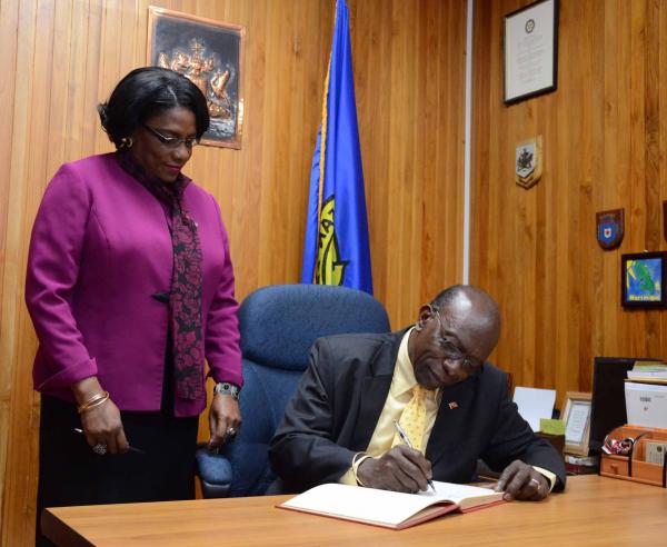Acting Prime Minister and Minister of Works and Infrastructure Jack Warner sign the visitors' book at the San Fernando City Hall. Looking on is San Fernando Mayor Marlene Coudray